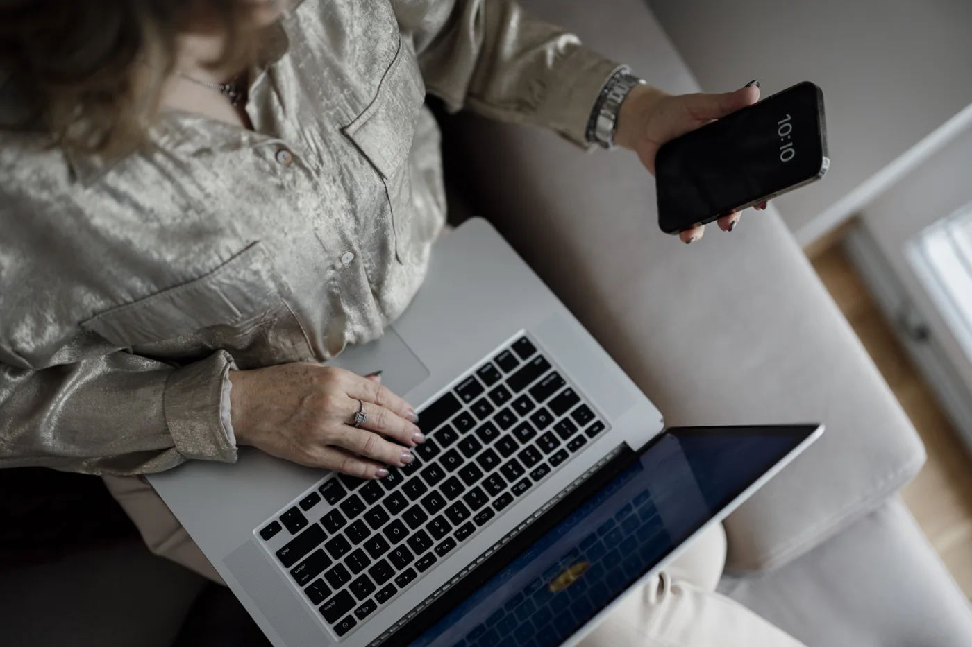 Trader checking smartphone alerts while using laptop for forex indicator signals
